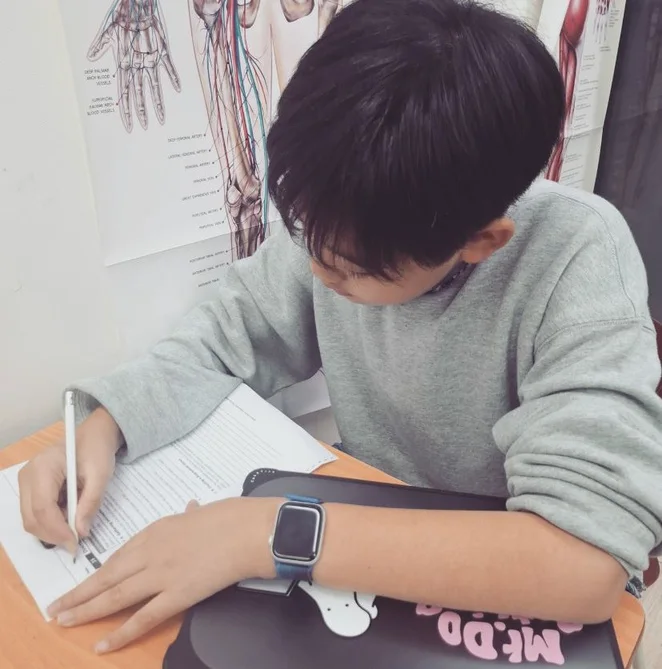 A student filling out an English writing worksheet at a desk