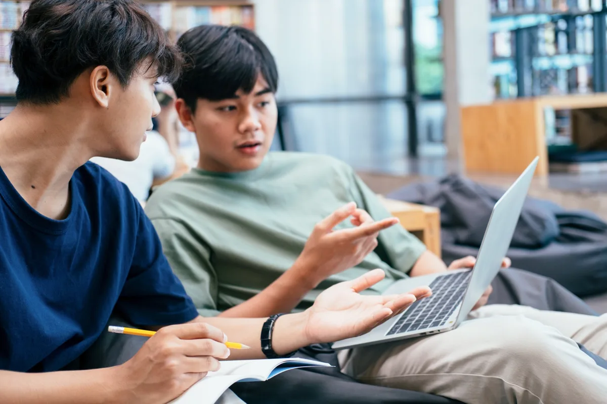 Two students talking in front of a laptop