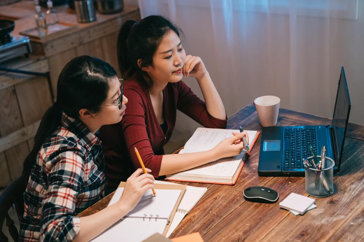 Two students writing in notebooks