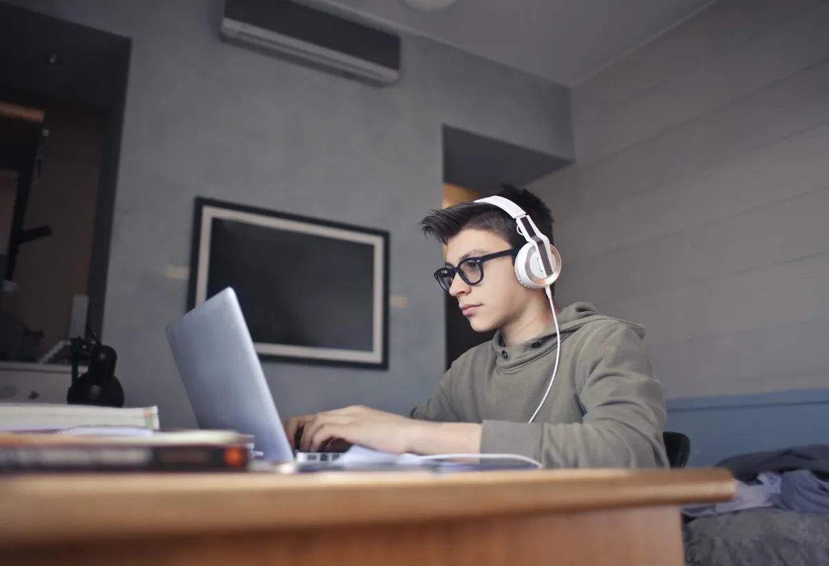 A student wearing headphones, sitting at a laptop and working on problems on the screen