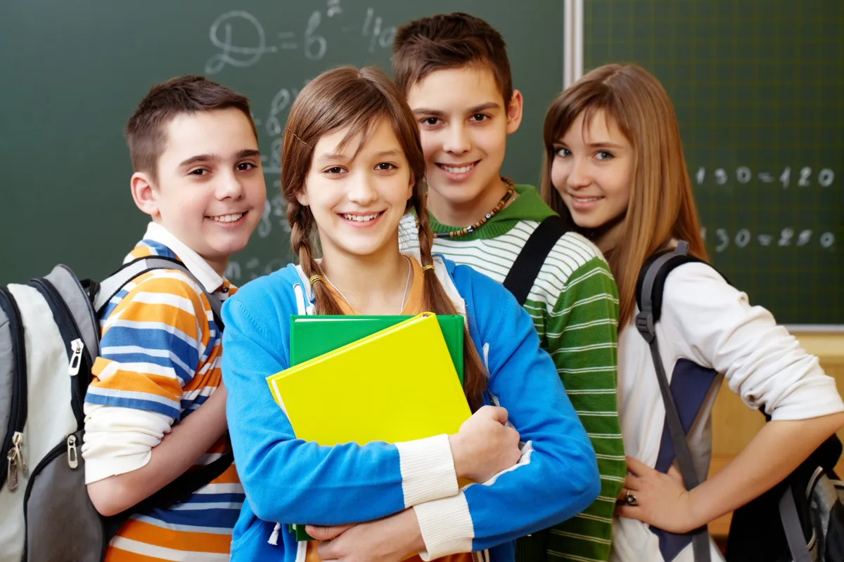Students holding notebooks in front of a blackboard